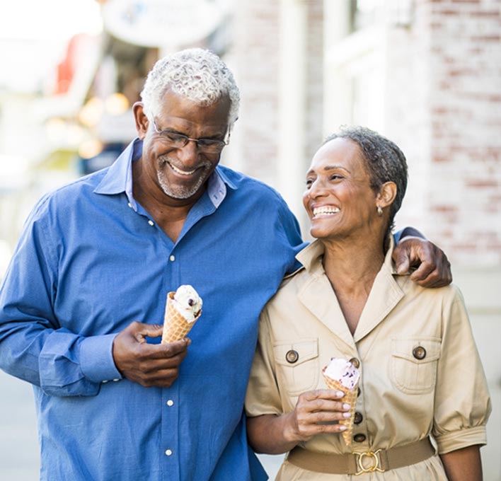 A couple walking down the street together, laughing and eating ice cream